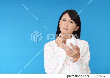 穿著睡衣與智能手機的女人 穿著睡衣與智能手機的女人 68776675