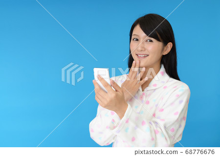 穿著睡衣與智能手機的女人 穿著睡衣與智能手機的女人 68776676