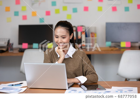 Happy Asian business woman in casual working with laptop and smile looking Happy Asian business woman in casual working with laptop and smile looking 68777058