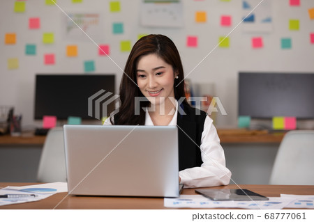 Happy Asian business woman in casual working with laptop and smile looking Happy Asian business woman in casual working with laptop and smile looking 68777061