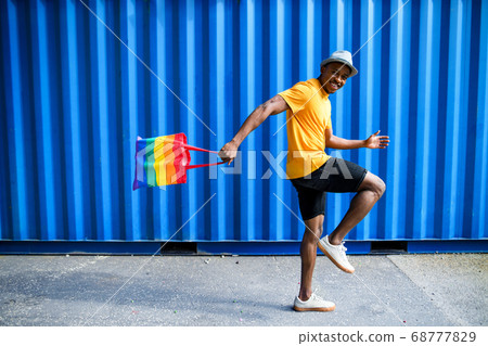 Young black man with rainbow bag walking, black lives matter concept. Young black man with rainbow bag walking, black lives matter concept. 68777829