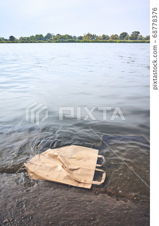 Discarded shopping paper bag in water. 68778376