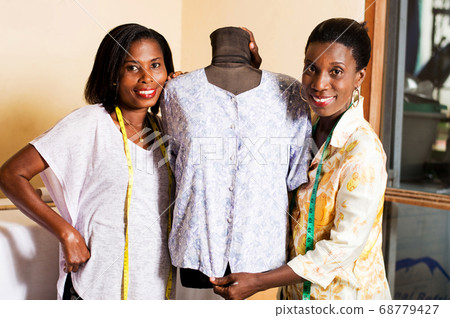 Smiling seamstress standing near a mannequin 68779427