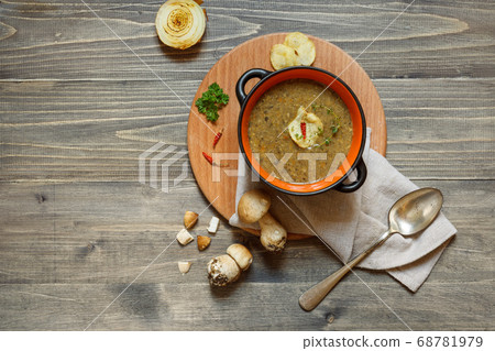 A portion of mushroom soup in a bowl, served on a round wooden Board with chips and hot pepper. Top view on a wooden background, with space A portion of mushroom soup in a bowl, served on a round wooden Board with chips and hot pepper. Top view on a wooden background, with space 68781979