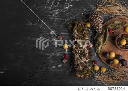 Berry mix on a wooden platter with oak branches and cones aside on the right 68783014