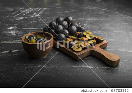 Whole and sliced black plums on a wooden board, angle view Whole and sliced black plums on a wooden board, angle view 68783512