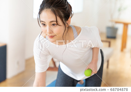 Young woman doing strength training with dumbbells in the room 68784878