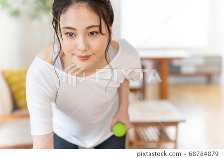 Young woman doing strength training with dumbbells in the room 68784879