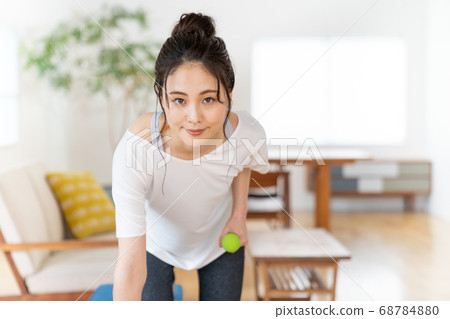 Young woman doing strength training with dumbbells in the room Young woman doing strength training with dumbbells in the room 68784880