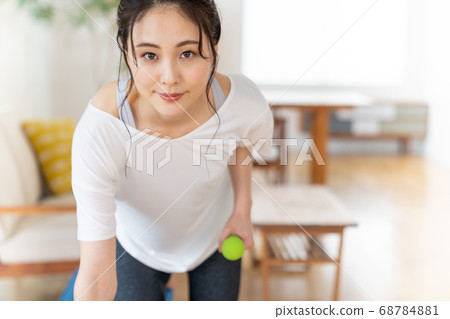 Young woman doing strength training with dumbbells in the room 68784881