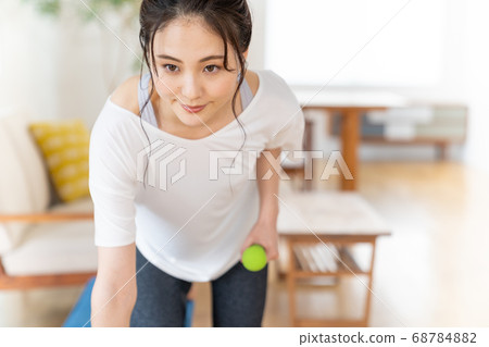 Young woman doing strength training with dumbbells in the room 68784882
