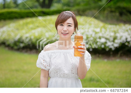 Woman drinking tea from a plastic bottle 68787284