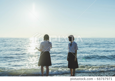 Schoolgirl in the sea at sunset 68787971