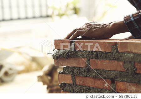 Bricklayer worker installing brick masonry 68790115