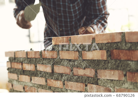 Bricklayer worker installing brick masonry Bricklayer worker installing brick masonry 68790126