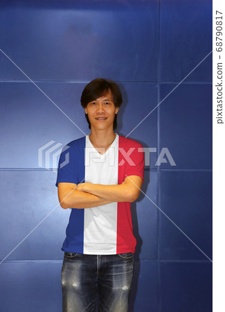 Man wearing France flag pattern shirt and cross one's arm on the blue wall background Man wearing France flag pattern shirt and cross one's arm on the blue wall background 68790817