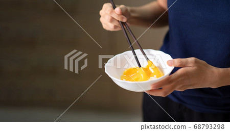 Woman beating eggs with chopsticks closeup Woman beating eggs with chopsticks closeup 68793298