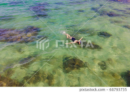 The woman is snorkeling among the corals. View from the drone The woman is snorkeling among the corals. View from the drone 68793735