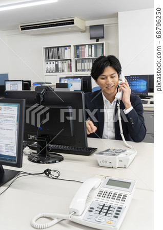 A young man making a phone call while working on a company disk A young man making a phone call while working on a company disk 68796250