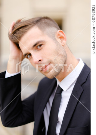Closeup portrait of young man wearing balck suit and tie. 68798922