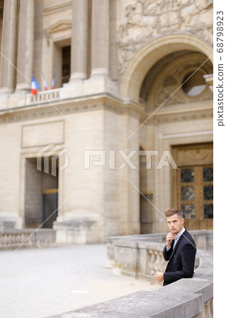 Young european groom waiting and leaning on concrete banister near building. Young european groom waiting and leaning on concrete banister near building. 68798923