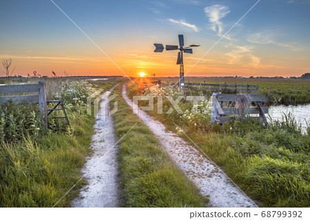 Old windmill in agricultural landscape 68799392