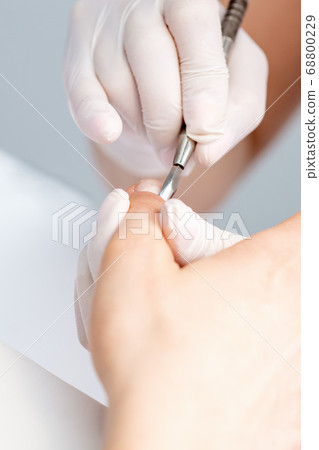 Woman receiving nail care procedure Woman receiving nail care procedure 68800229