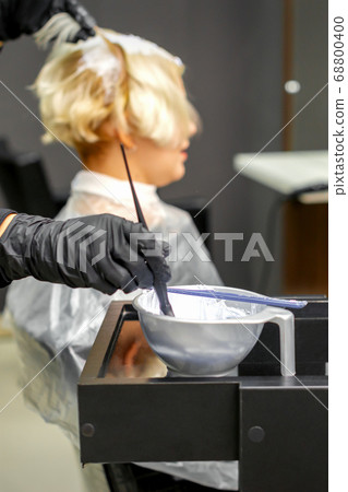 Hairdresser dyeing hair of young woman 68800400