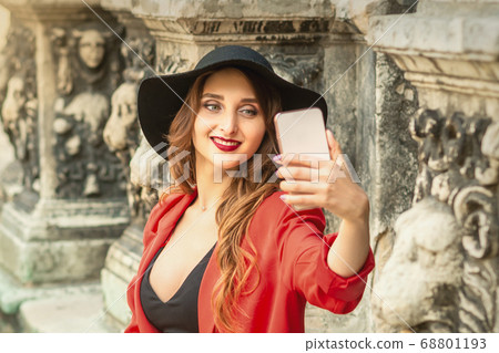 Pretty tourist girl is taking a selfie. 68801193