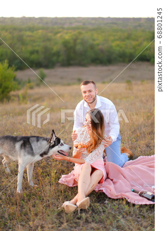 Young european girl and boy sitting on pink plaid near husky and resting. Young european girl and boy sitting on pink plaid near husky and resting. 68801245