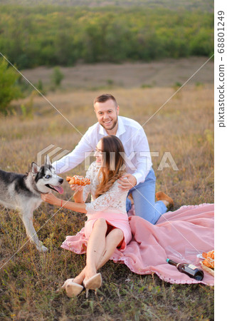 Young girl and boy sitting on pink plaid near husky and resting. Young girl and boy sitting on pink plaid near husky and resting. 68801249
