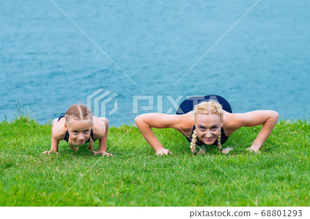 Little girt and woman are doing exercises Little girt and woman are doing exercises 68801293