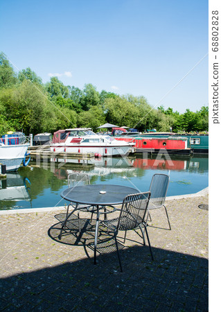 Canal boat arena and cafe chairs and tables with dazzling sunlight in the suburbs of London 68802828