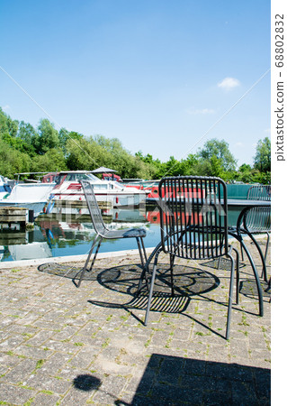 Canal boat arena and cafe chairs and tables with dazzling sunlight in the suburbs of London 68802832