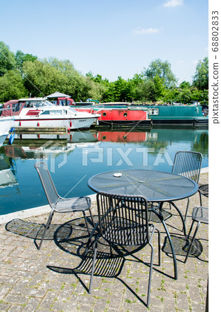 Canal boat arena and cafe chairs and tables with dazzling sunlight in the suburbs of London 68802833