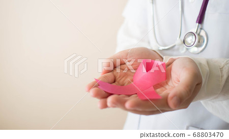 International symbol of Breast Cancer Awareness Month in October. Female doctor hand holding pink ribbon awareness for support people who live with breast cancer. Women health care concept. 68803470