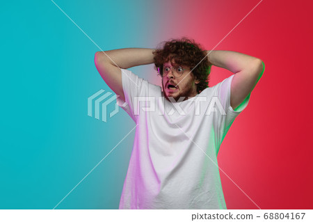 Caucasian young man's portrait on gradient studio background in neon 68804167