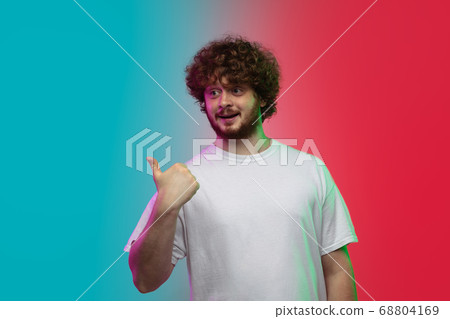Caucasian young man's portrait on gradient studio background in neon 68804169