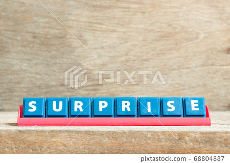 Tile letter on red rack in word surprise on wood background Tile letter on red rack in word surprise on wood background 68804887