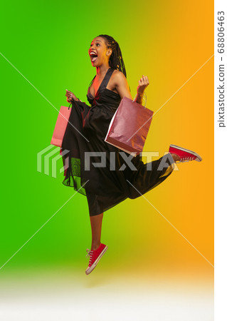 Portrait of young woman in neon light on gradient backgound. The human emotions, black friday, cyber monday, purchases, sales, finance concept. Portrait of young woman in neon light on gradient backgound. The human emotions, black friday, cyber monday, purchases, sales, finance concept. 68806463