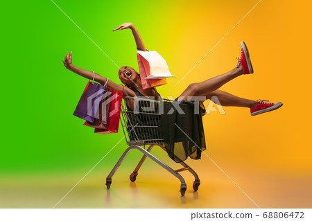 Portrait of young woman in neon light on gradient backgound. The human emotions, black friday, cyber monday, purchases, sales, finance concept. Portrait of young woman in neon light on gradient backgound. The human emotions, black friday, cyber monday, purchases, sales, finance concept. 68806472
