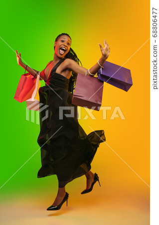 Portrait of young woman in neon light on gradient backgound. The human emotions, black friday, cyber monday, purchases, sales, finance concept. Portrait of young woman in neon light on gradient backgound. The human emotions, black friday, cyber monday, purchases, sales, finance concept. 68806477