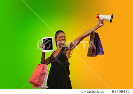 Portrait of young woman in neon light on gradient backgound. The human emotions, black friday, cyber monday, purchases, sales, finance concept. Portrait of young woman in neon light on gradient backgound. The human emotions, black friday, cyber monday, purchases, sales, finance concept. 68806482