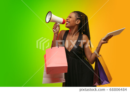 Portrait of young woman in neon light on gradient backgound. The human emotions, black friday, cyber monday, purchases, sales, finance concept. Portrait of young woman in neon light on gradient backgound. The human emotions, black friday, cyber monday, purchases, sales, finance concept. 68806484