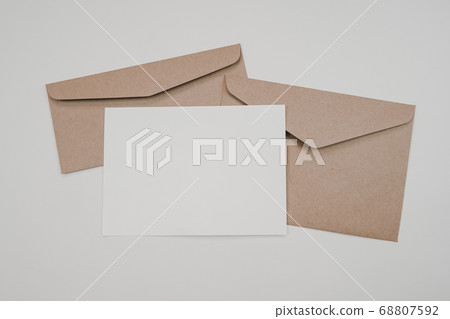 Blank white paper on the two brown paper envelope. Mock-up of horizontal blank greeting card. Top view of Craft paper envelope on white background. Flat lay of stationery. Minimalism style. Blank white paper on the two brown paper envelope. Mock-up of horizontal blank greeting card. Top view of Craft paper envelope on white background. Flat lay of stationery. Minimalism style. 68807592