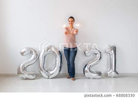 New Year celebration and party concept - Happy young woman with sparklers near silver 2021 balloons on white background. 68808330