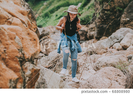 woman with backpack walking on the rock by river woman with backpack walking on the rock by river 68808980