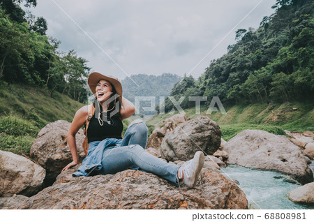 Happy woman laughing while sitting on the rock by Happy woman laughing while sitting on the rock by 68808981