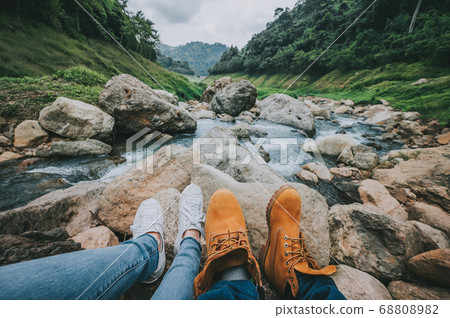 Feet of couple relaxing while sitting by river in Feet of couple relaxing while sitting by river in 68808982