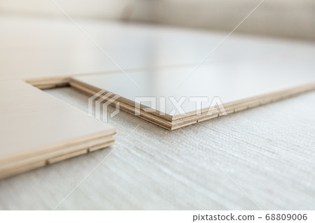 Engineered wood floor installation with subfloor membrane in condo. Maple hardwood flooring planks closeup showing composite plywood layers. Remodeling home improvement concept Engineered wood floor installation with subfloor membrane in condo. Maple hardwood flooring planks closeup showing composite plywood layers. Remodeling home improvement concept 68809006